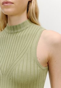 Rippenträgershirt in gedämpftem Olivgrün, mit hohem Kragen, subtiler Textur und V-förmigen Details auf der Vorderseite.