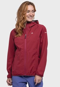 Red lightweight jacket with a zip front, hood, and elastic cuffs. Features a logo on the left shoulder and side pockets.