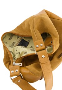 Handtasche aus Wildleder und Leder in Senfgelb, mit einer weichen Textur. Das Innere ist mit einem beigen Futter ausgestattet, das wiederholt das Markenlogo zeigt, sowie einer Reißverschlusstasche.