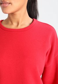 Rode sweatshirt met een ronde halslijn en een zachte textuur, met zichtbaar stiksel en een relaxte pasvorm.