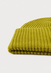 Ribbed knit beanie in olive green, featuring a soft texture and folded brim. Crafted from stretchy yarn for a snug fit.