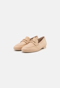 Beige zamšveidīgi loaferi ar gludu apdari, noapaļotu purngalu un dekoratīvu augšējo šuvju. Zema profila papēdis un uzvelkams dizains.