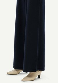 Marina vida byxorna med en mjuk textur, matchade med spetsiga, beige klackar med en liten blockklack och sömdekor.