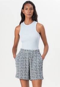 Light blue ribbed tank top paired with patterned white shorts featuring blue geometric designs; shorts have side pockets and an elastic waistband.