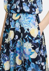 Blumenkleid mit navy Hintergrund, blauen und gelben Blumen, weichem Stoff und einer Taschennaht an der Taille.