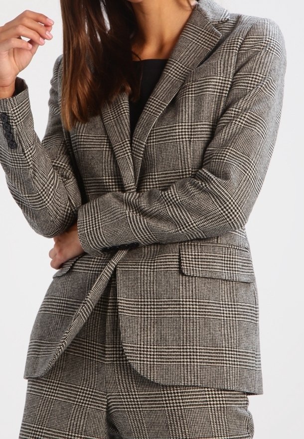 Grå rutmönstrad kavaj med strukturerade slag, enknappsstängning och två framfickor, med en texturerad tygkvalitet i klassiskt rutmönster.