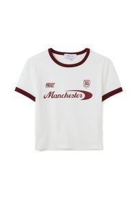 Camiseta de manga corta blanca con detalles en color burdeos, que presenta el texto "Manchester" y diseños gráficos, fabricada en algodón. Estilo de cuello redondo.