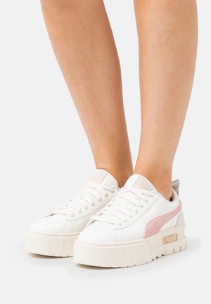 Zapatillas de plataforma blancas con acentos en rosa y gris, parte superior de cuero suave, puntera redonda y suela texturada. Incluye cordones y detalle del logo.