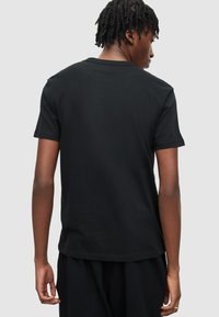 �Černé bavlněné tričko s krátkým rukávem, kulatým výstřihem a volným střihem. Tkanina vypadá hladce, bez viditelných vzorů nebo akcentů.