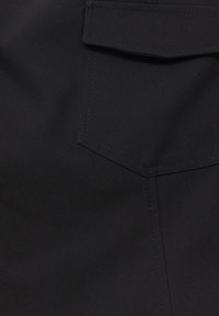 Tissu noir au toucher lisse, comportant une poche rectangulaire et des détails de couture droite le long des bords.