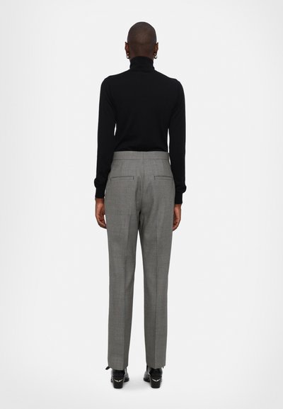 Crna turtleneck pulover uparen s hlačama od sive karirane tkanine visoko strukirane; glatka tekstura s stražnjim džepovima i elegantnim dizajnom ravnog kroja.