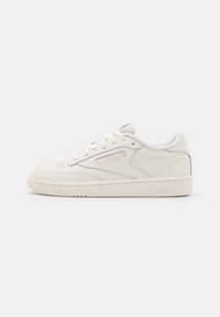 Baskets en cuir blanc avec bout rond, silhouette basse, semelle en caoutchouc texturée, et logo Reebok sur le côté et le talon. Les lacets sont plats et ivoire.