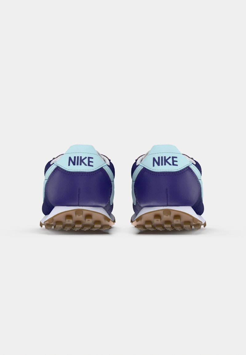 Un par de zapatillas Nike azul y azul claro vistas desde atrás, con suelas marrones texturizadas visibles sobre un fondo blanco.