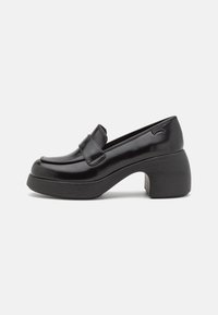 Mocassins à plateforme en cuir verni noir avec un bout rond, une bande décorative et un talon chunky sculpté avec une finition mate.