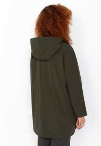 Giacca con cappuccio verde oliva, dal taglio rilassato, con vita cinchata, maniche lunghe e tessuto liscio e impermeabile.