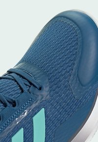 Scarpa da ginnastica blu con tomaia in maglia testurizzata, dettagli lisci e particolari in teal. Presenta lacci e una suola imbottita.