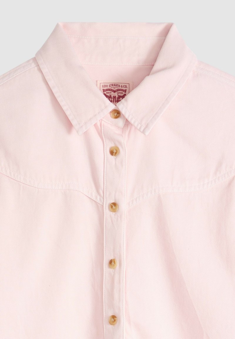 Chemise rose clair boutonnée avec col pointu et cinq boutons beige, montrant l'étiquette Levi Strauss & Co. à l'intérieur du col.