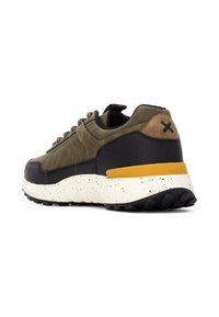 Zapatillas para hombre en ante verde oliva con detalles en goma negra. Presentan una suela blanca salpicada y una etiqueta naranja en el talón.