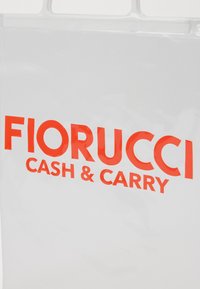 Gjennomsiktig plastpose med fet rød tekst som sier "FIORUCCI CASH & CARRY." Jevn tekstur og rektangulær form med utsparinger for håndtak.