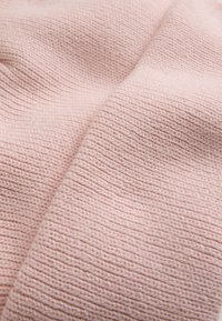 Heller rosa gestrickter Stoff mit einem strukturierten Muster und gleichmäßig verteilten horizontalen Reihen von Stichen, was ihm ein weiches, warmes Aussehen verleiht.