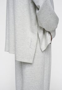 Top in morbido tessuto grigio chiaro con maniche lunghe, fessure laterali e un evidente dettaglio della cucitura sulla manica. Vestibilità rilassata; abbinato a pantaloni coordinati.