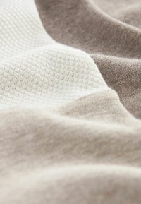 Tissu présentant trois sections : beige doux, crème texturé avec un motif en nid d'abeille, et brun clair lisse. Variations subtiles de couleur visibles.