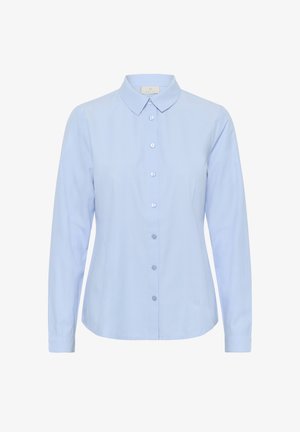 Gai zils krekliņš, izgatavots no kokvilnas, ar klasisku apkakli, pogu priekšpusi, garām piedurknēm un izliekto apakšmalu. Gluda tekstūra, minimāls dizains.