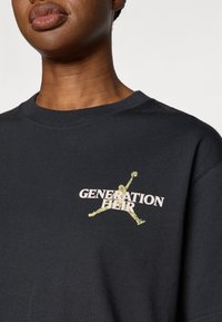 Μαύρο φούτερ από βαμβάκι με το κείμενο "GENERATION HEIR" σε ροζ, και με μια κίτρινη σιλουέτα σχεδίαση μπροστά. Με στρογγυλή λαιμόκοψη και άνετη εφαρμογή.