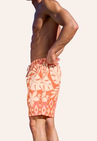 Pantaloni da bagno arancioni con motivo floreale e geometrico, dotati di una vita elasticizzata, coulisse e tessuto leggero.