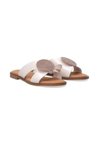 White leather sandals with a flat sole, open design, and a circular decorative accent. Smooth texture and simple, minimalist shape.