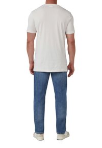 Witte katoenen T-shirt met korte mouwen, ronde halslijn en een relaxte pasvorm, gecombineerd met lichtblauwe denim jeans en witte sneakers.