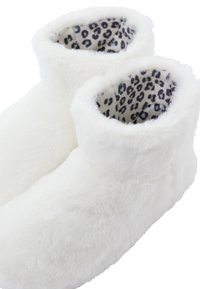 Białe kapcie botki z sztucznego futra, z miękkim i puszystym wierzchem oraz podszewką w leopardzi wzór. Rąbek jest zrolowany, co nadaje swobodny wygląd.
