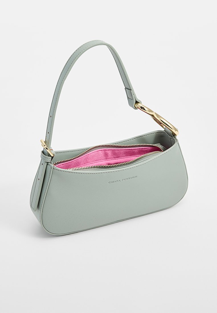 Hellgrüne Lederhandtasche mit goldener Schnalle, gebogenem oberen Griff und offener Reißverschluss, der das leuchtend pinke Innenfutter enthüllt.