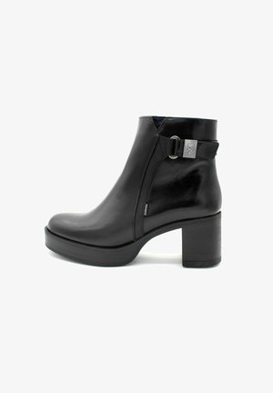 Bottine en cuir noir avec une finition lisse, bout rond et un talon bloc de hauteur intermédiaire. Comprend une fermeture éclair latérale et une boucle en métal argenté.