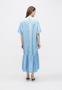 Svetlomodré saténové šaty s krátkymi rukávmi, guľatým výstrihom a volánovým lemom. Zadná časť má vertikálny rozparok a hladkú textúru.