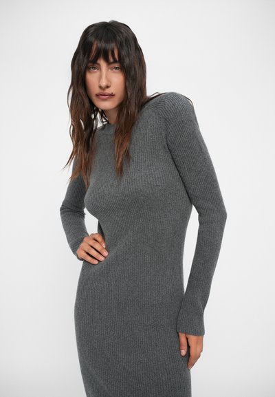 Robe longue à manches longues grise côtelée en tissu texturé, avec un col rond et une silhouette cintrée, ornée de légères lignes verticales.