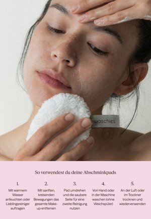 Young person gently cleanses face with a white reusable makeup remover pad labeled "waschies" against a plain background.