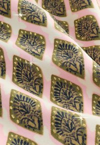 Tessuto rosa con forme di diamante verdi ripetute che presentano motivi botanici scuri e piccoli accenti di glitter dorato.