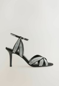 Sandale à talon haut noire avec plusieurs brides ornées de strass brillants. Dotée d'une bride à la cheville et d'un design élégant à bout pointu.