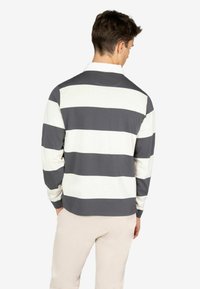 Camicia a maniche lunghe a righe grigie e bianche, con colletto e vestibilità rilassata. Il tessuto sembra morbido e leggermente strutturato.