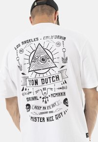 Camiseta blanca con un estampado gráfico negro en la parte posterior, que incluye un ojo dentro de un triángulo, calaveras y varios elementos de texto.