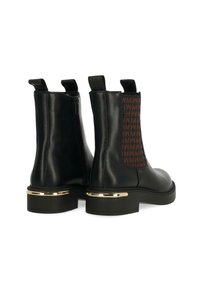 Černé kožené kotníkové boty s texturovanou hnědou boční panelem s logem. Zlaté akcenty na podpatku dodávají detail.