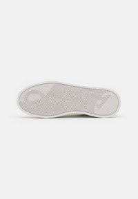 Suela de zapato de goma blanca con patrón de espiga texturizado y detalle del logo en relieve. Punta redondeada y bordes suaves. Diseño minimalista.