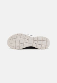 Suela de zapato con un caucho blanco texturizado y un patrón en cuadrícula para tracción, mostrando una ligera curvatura y una superficie uniforme.