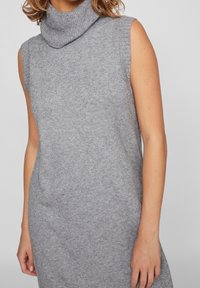 Grå stickad ärmlös klänning med hög krage. Texturen är mjuk och något elastisk, med en enkel, figurnära design.
