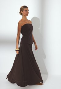 Strapless brown two-piece ensemble featuring a fitted top and flowing skirt, made of lightweight fabric with a smooth texture.