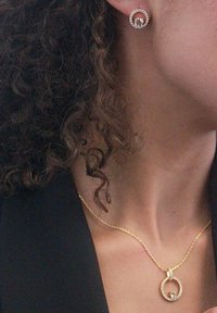 Gouden sieradenset met ronde, diamante-oorbellen en een bijpassende hanger ketting met een cirkelontwerp en kleine edelsteengegevens.