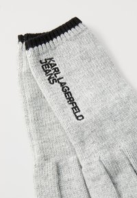 Szürke kötött kesztyű, fekete bordás mandzsettával, az egyik oldalon fekete hímzett "KARL LAGERFELD JEANS" felirattal.