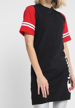Zwarte t-shirt jurk met korte rode mouwen met witte strepen. De voorkant toont een groot wit grafisch logo aan de zijkant. Gemaakt van katoen.