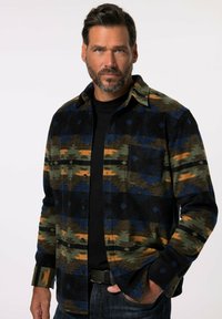 Rutig flannel skjorte i jordnære grønne, sorte og orange nuancer med knaplukning front og brystlomme. Blødt materiale og struktureret pasform.